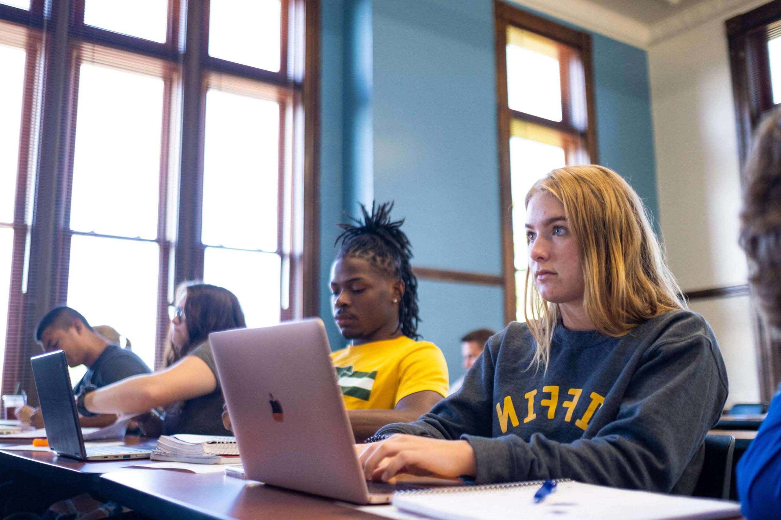 college students at laptop in classroom